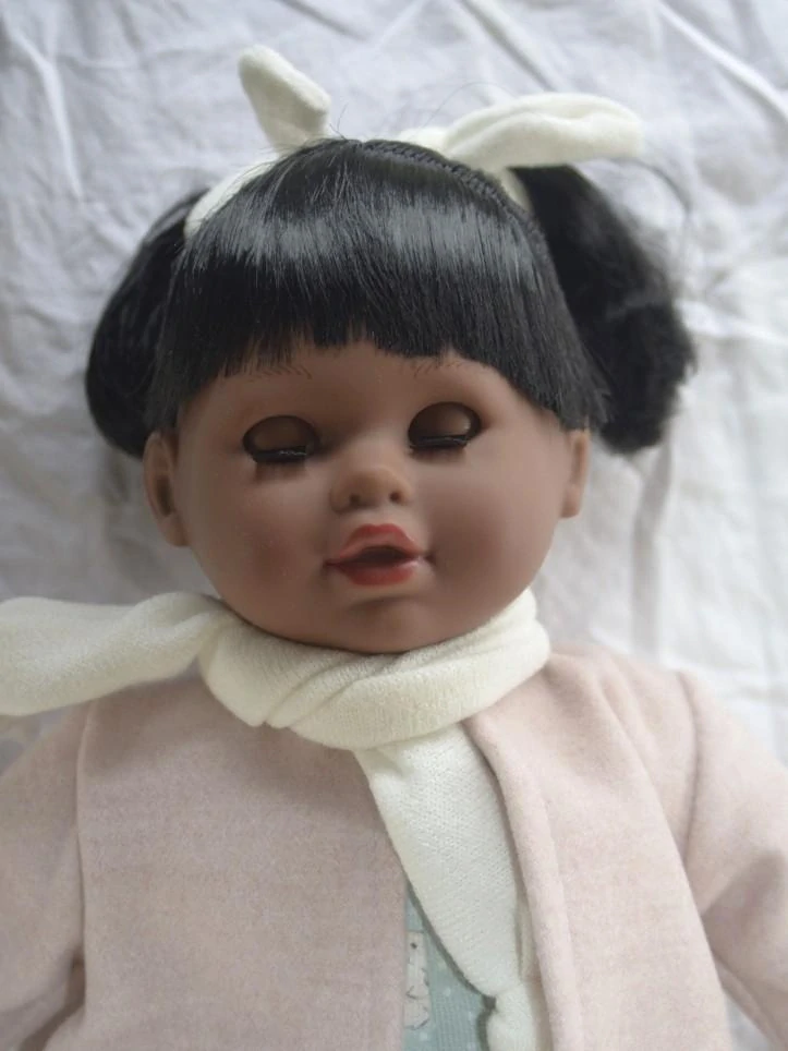 Snědá realistická panenka- Tina s bílou šálou kolem krku od španělské firmy Marina & Pau